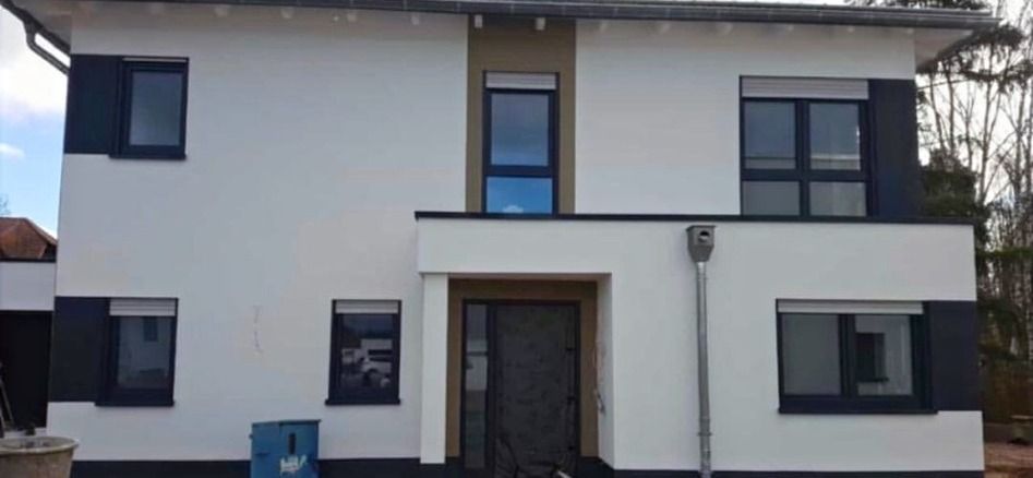 Fertige Fassade eines Einfamilienhauses in Weiß mit abgesetztem, dunklem Eingangsbereich.