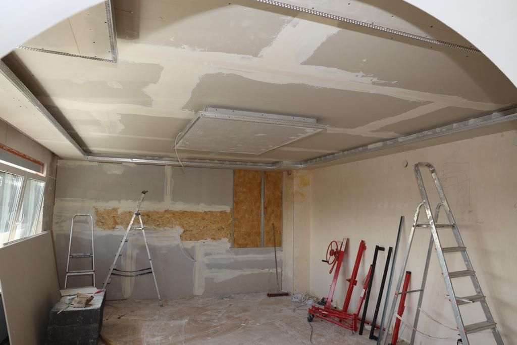 Raum im Ausbau: neue Decke aus Gipskarton mit gespachtelten Fugen, Leiter und Werkzeug.